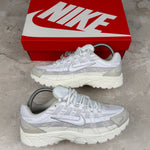 White and gray sneakers with a red Nike box on a concrete floor