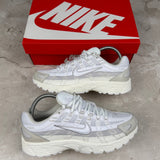 White and gray sneakers with a red Nike box on a concrete floor